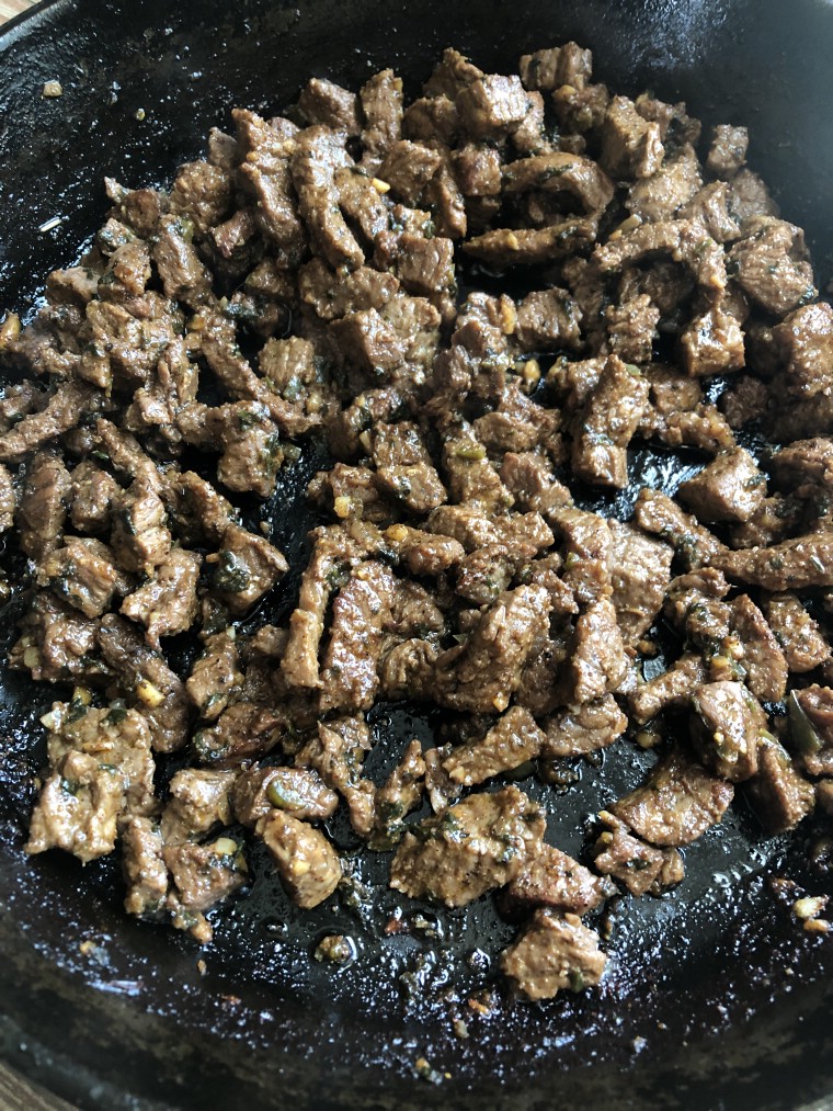 Beef being cooked in a cast iron skillet