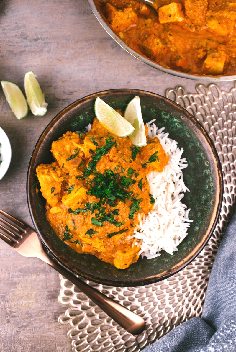 Curry chicken with lime wedges and cilantro