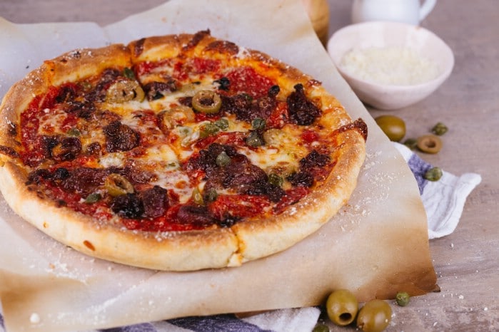 Pizza on pizza stone with cheese and olives