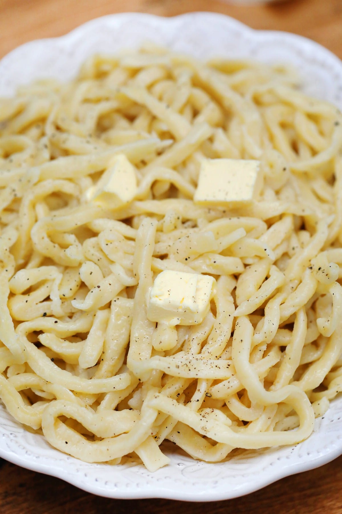 Egg noodles in white baking dish with butter