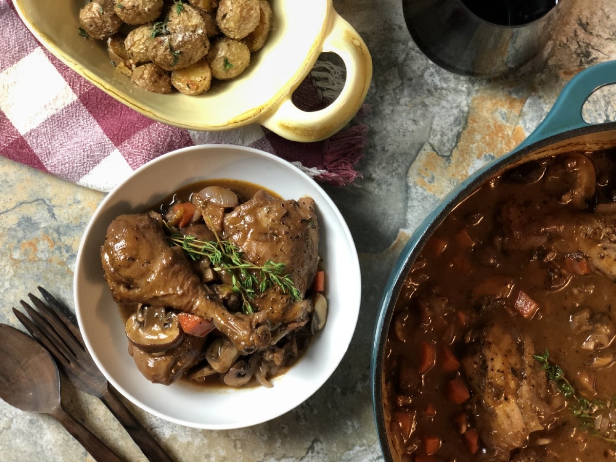 Coq au vin in bowls and skillet