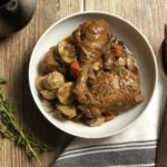 white bowl of coq au vin on wood table