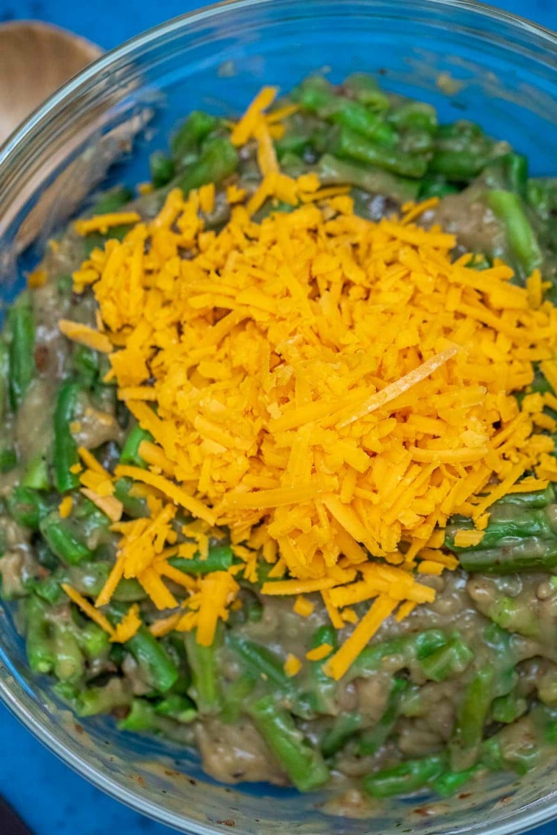 Glass bowl of green beans with cheese on top