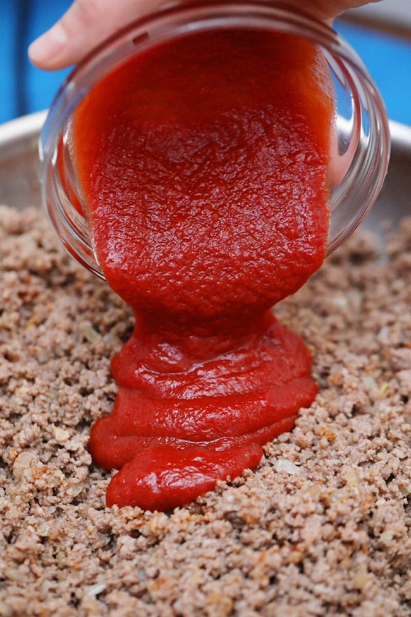 Pouring ketchup into ground meat