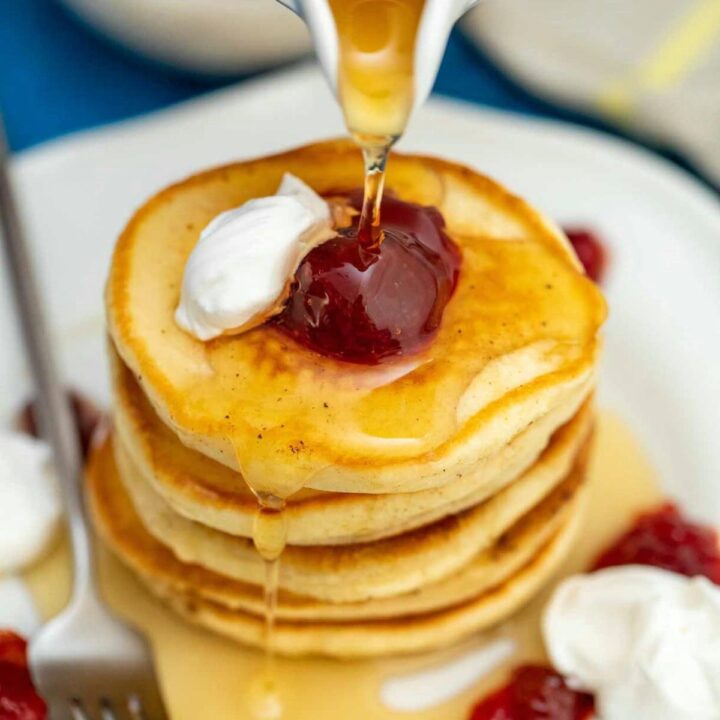 Pouring syrup over stack of flapjacks