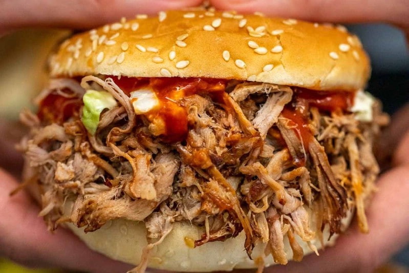 Woman holding pulled pork sandwich
