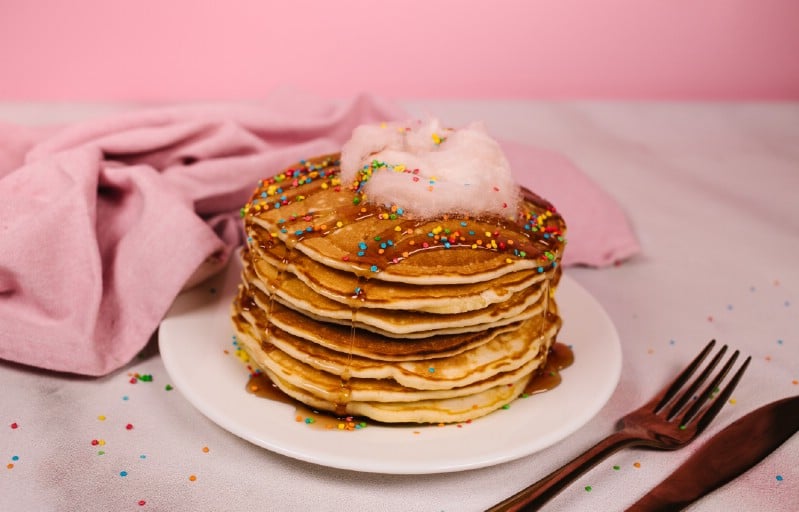 Stack of pancakes on white plate with pink napkin