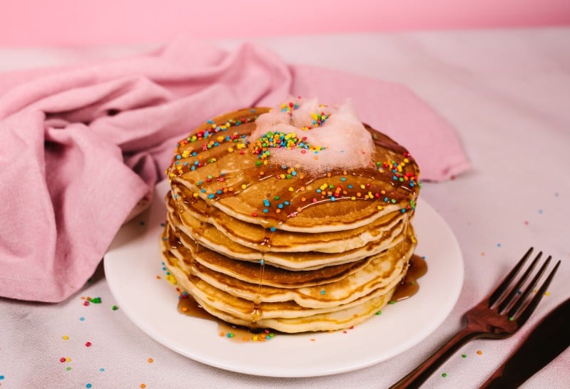 Stack of pancakes on white plate with pink napkin