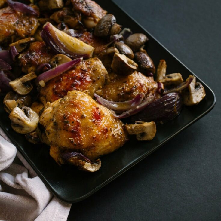 Chicken thighs and mushrooms on baking sheet