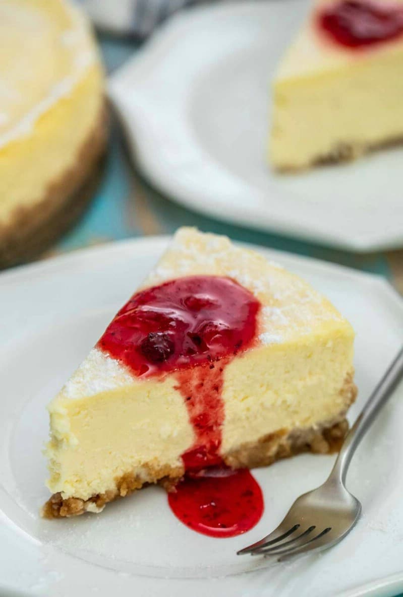 Slice of cheesecake on white plate with strawberry sauce