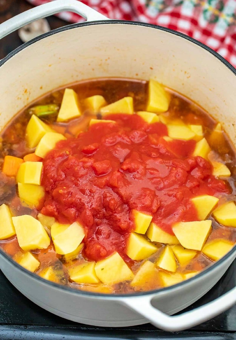 Adding potatoes and tomatoes to dutch oven