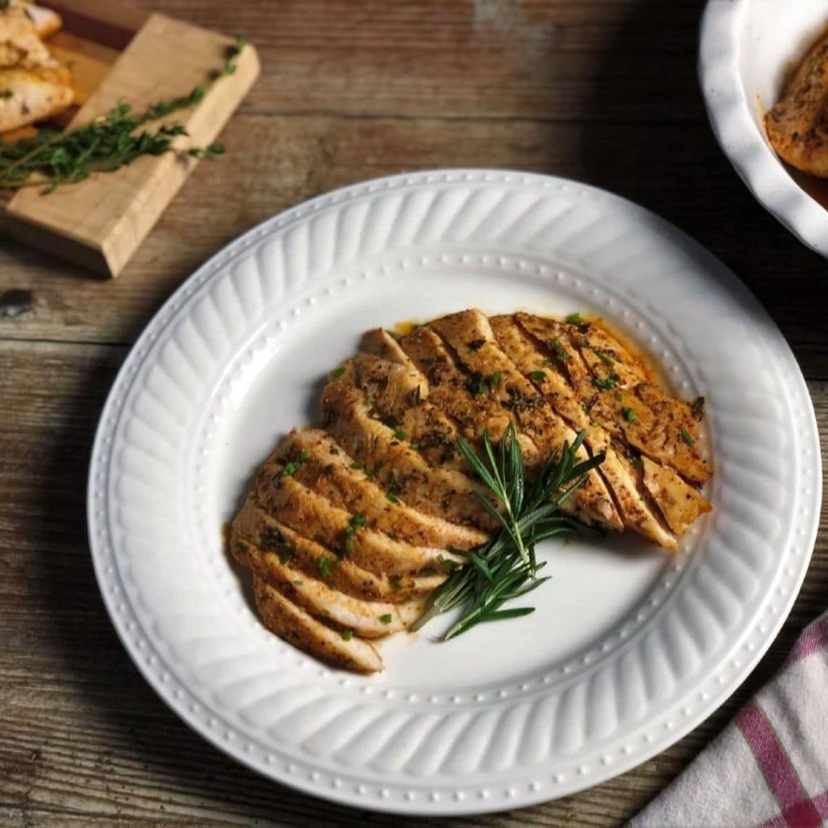 Baked garlic herb chicken breasts in a white plate.