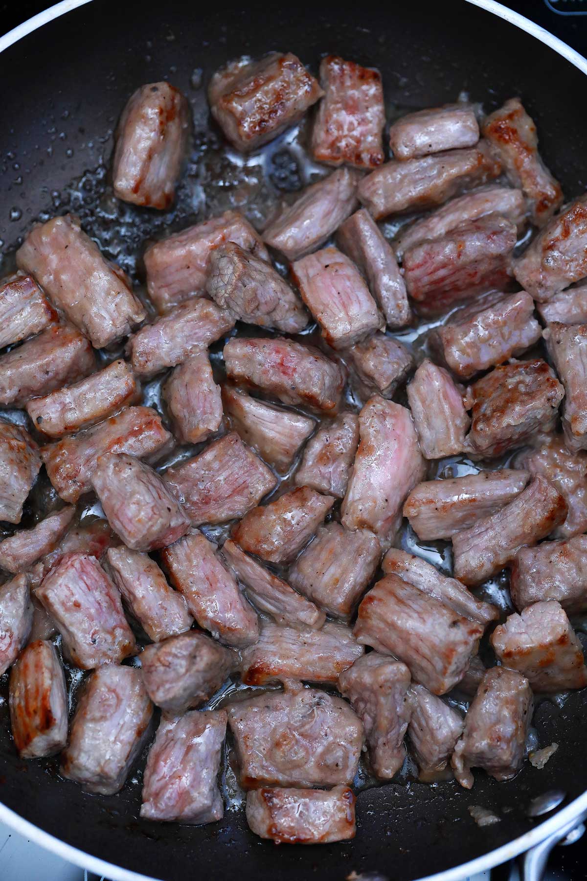 Beef chunks cooking in skillet