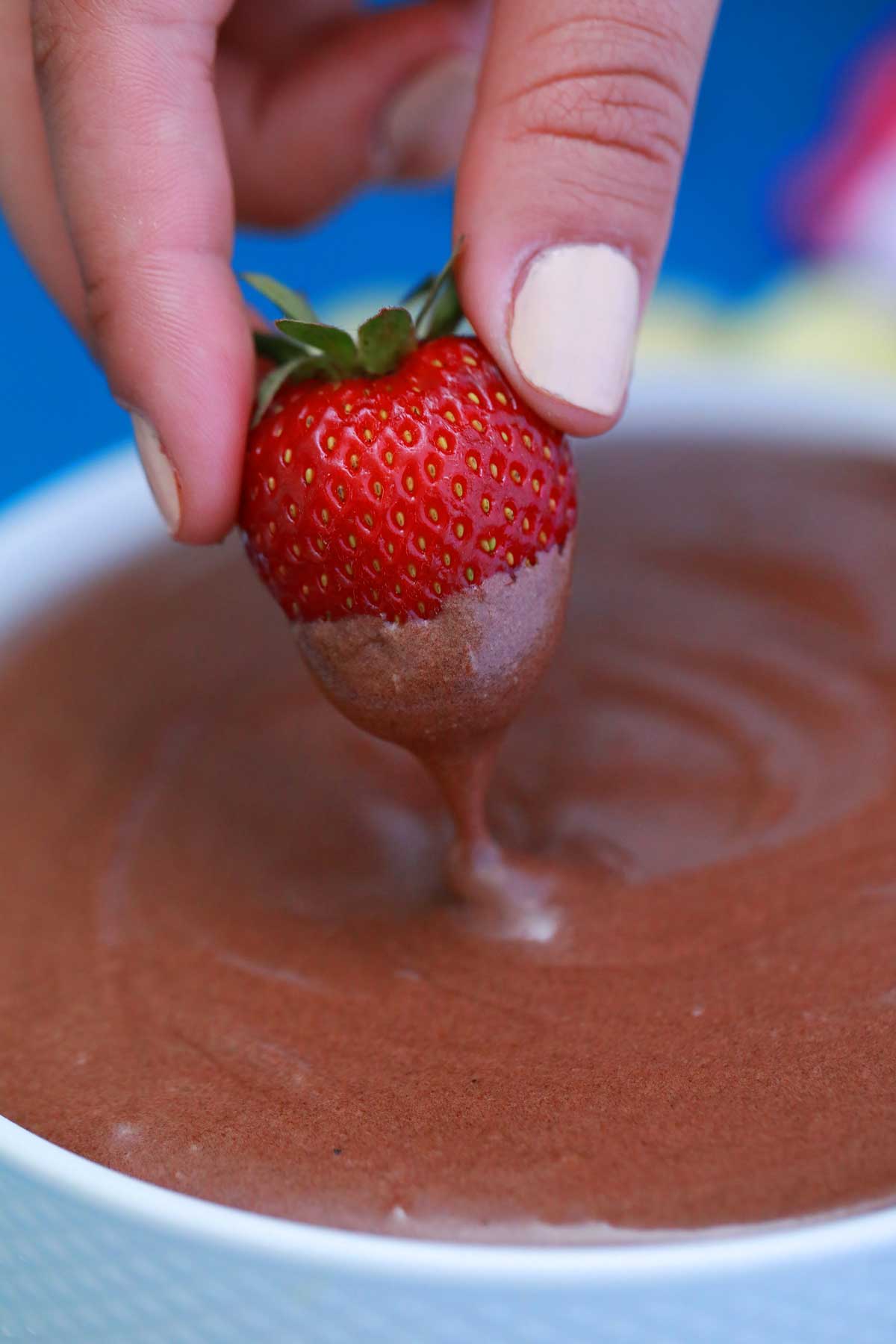 Hand dipping strawberry into dip