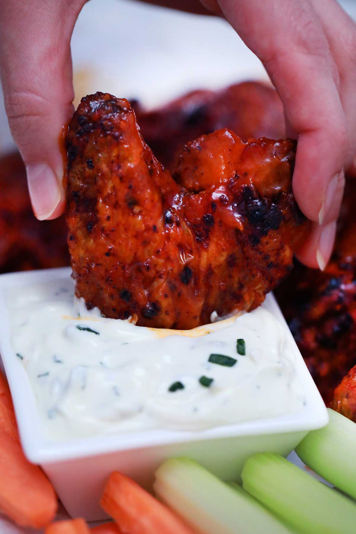 Hand dipping chicken wing