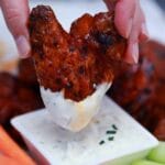 Hand dipping chicken wing