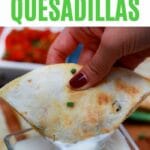 Hand dipping quesadilla in sour cream