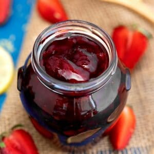 Strawberry jam in jar on cutting board
