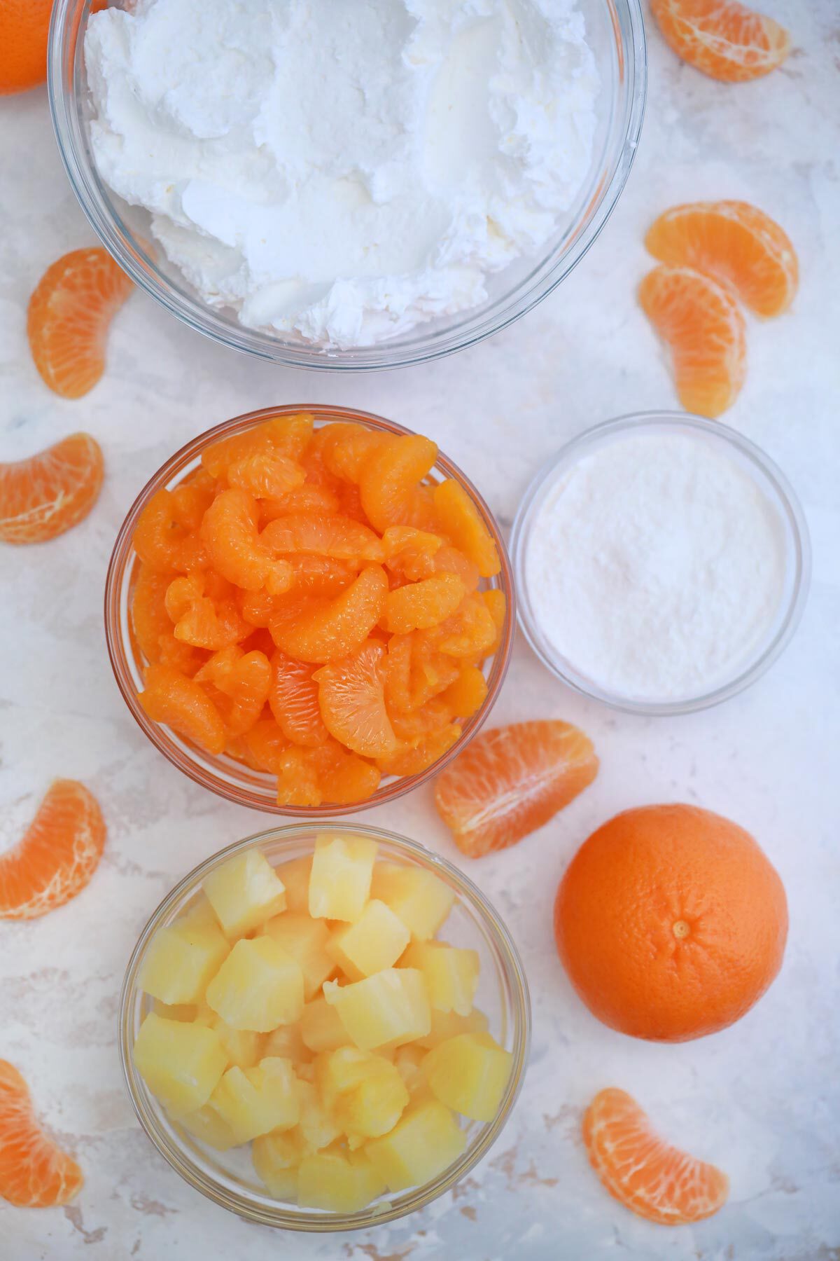 Ingredients for mandarin orange salad in glass bowls on marbled counter