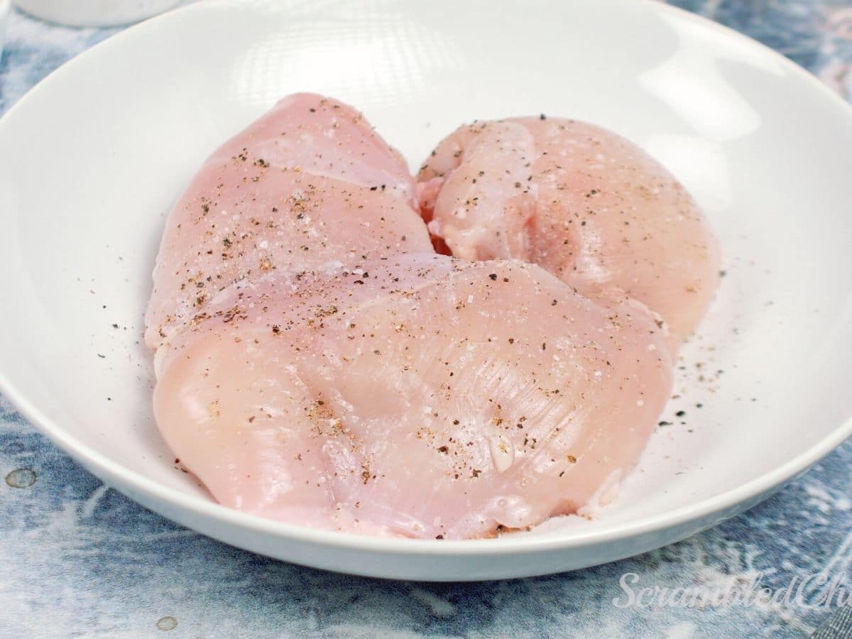 Seasoned chicken breasts in white bowl