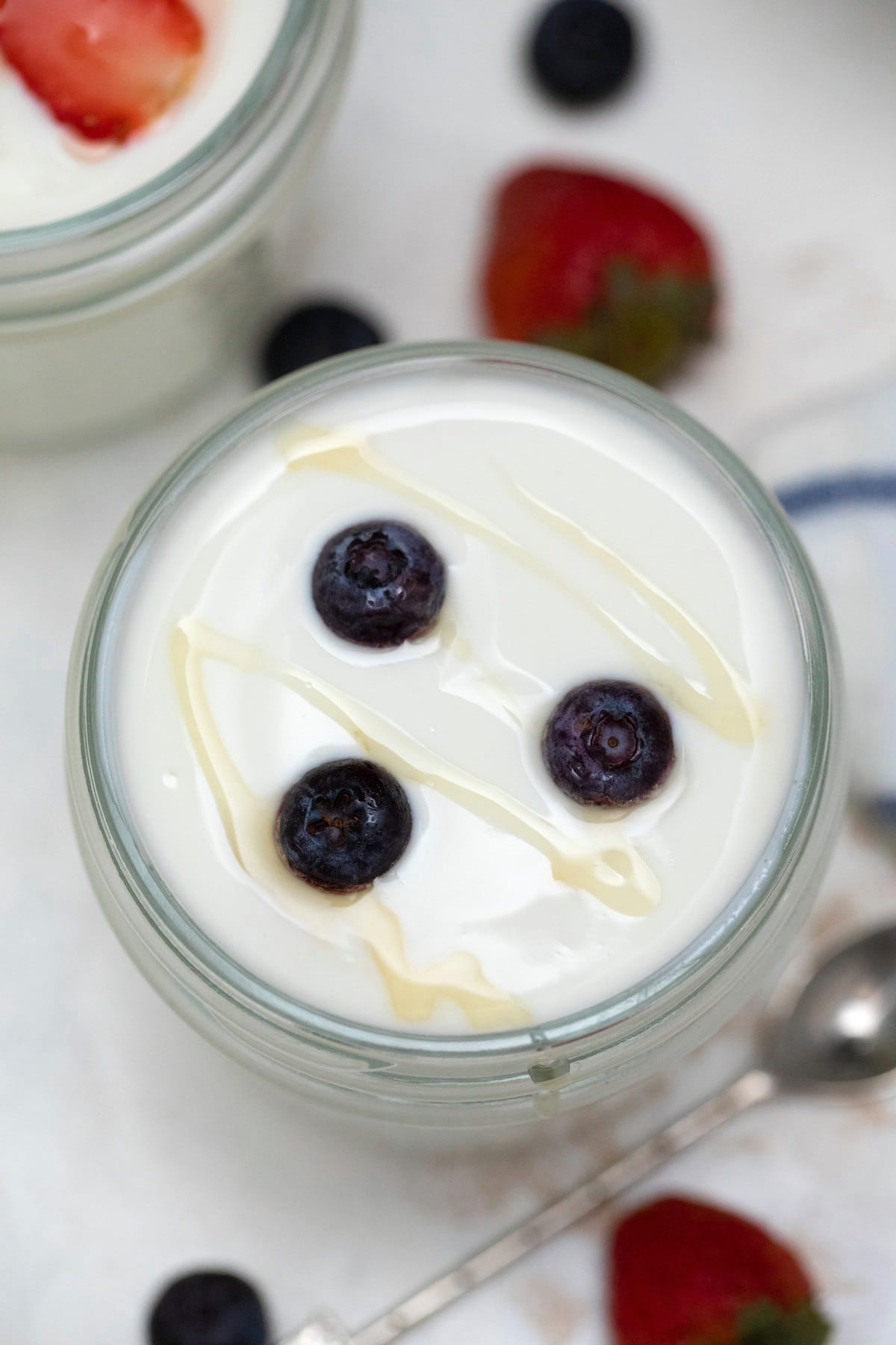 Glass jar of yogurt topped with blueberries and honey