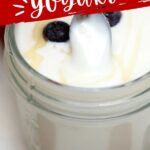 Glass jar of yogurt with blueberry and spoon just above