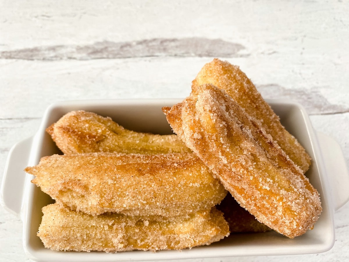 Churros stacked into a white bowl