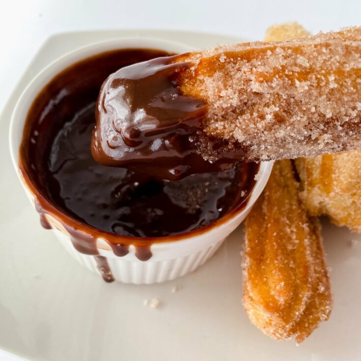 Churro being dipped into chocolate sauce