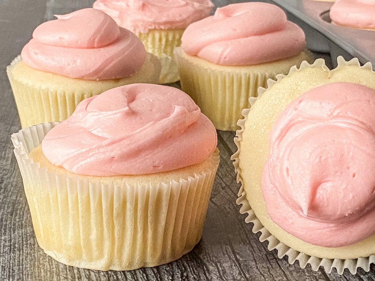 Cupcakes with pink icing on wood