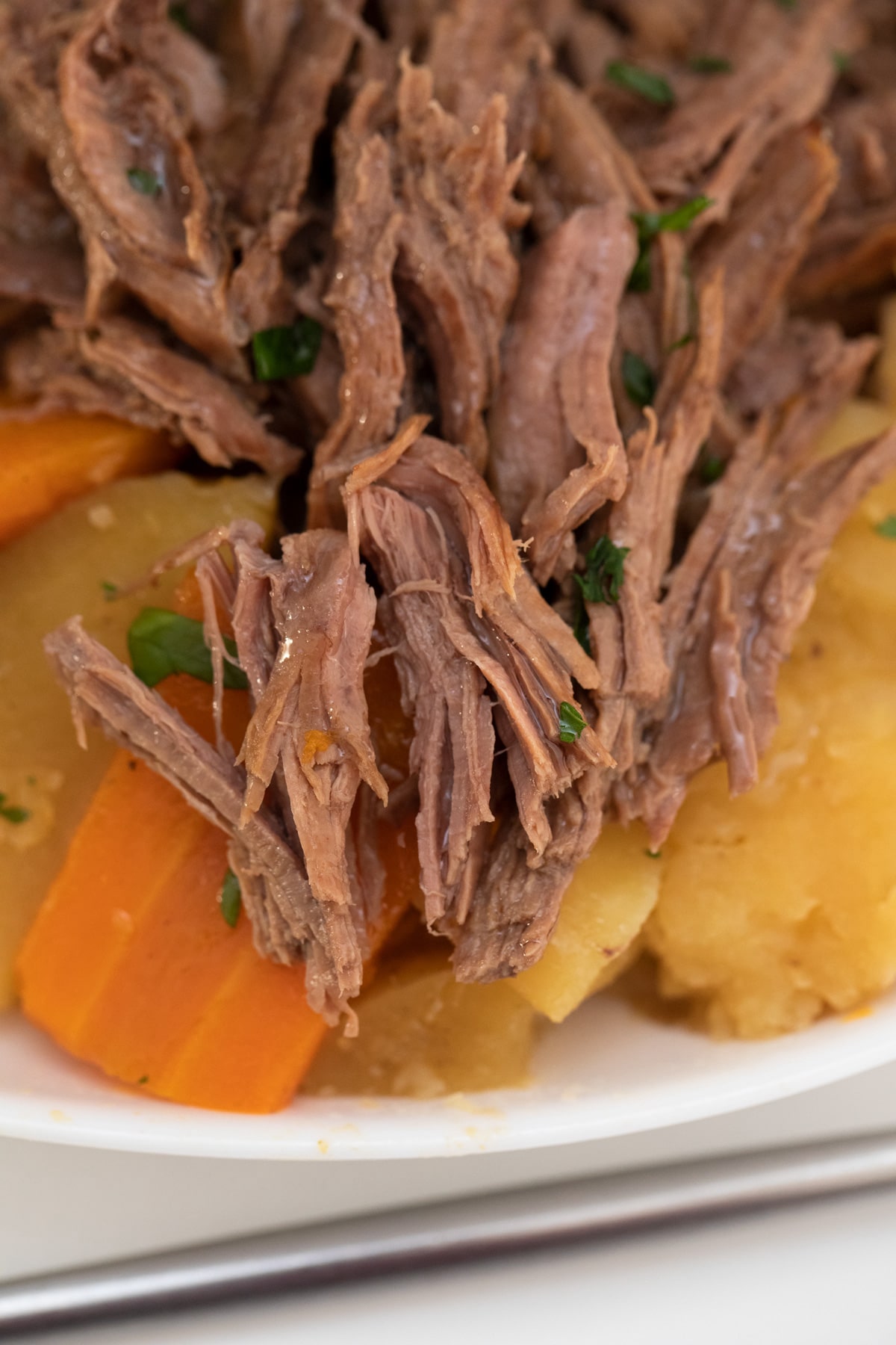 Shredded beef on top of cooked potatoes and carrots