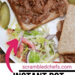 White plate with pulled pork on whole wheat and side salad