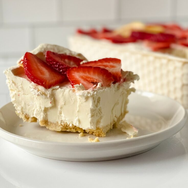 Slice of cheesecake with strawberries on white saucer