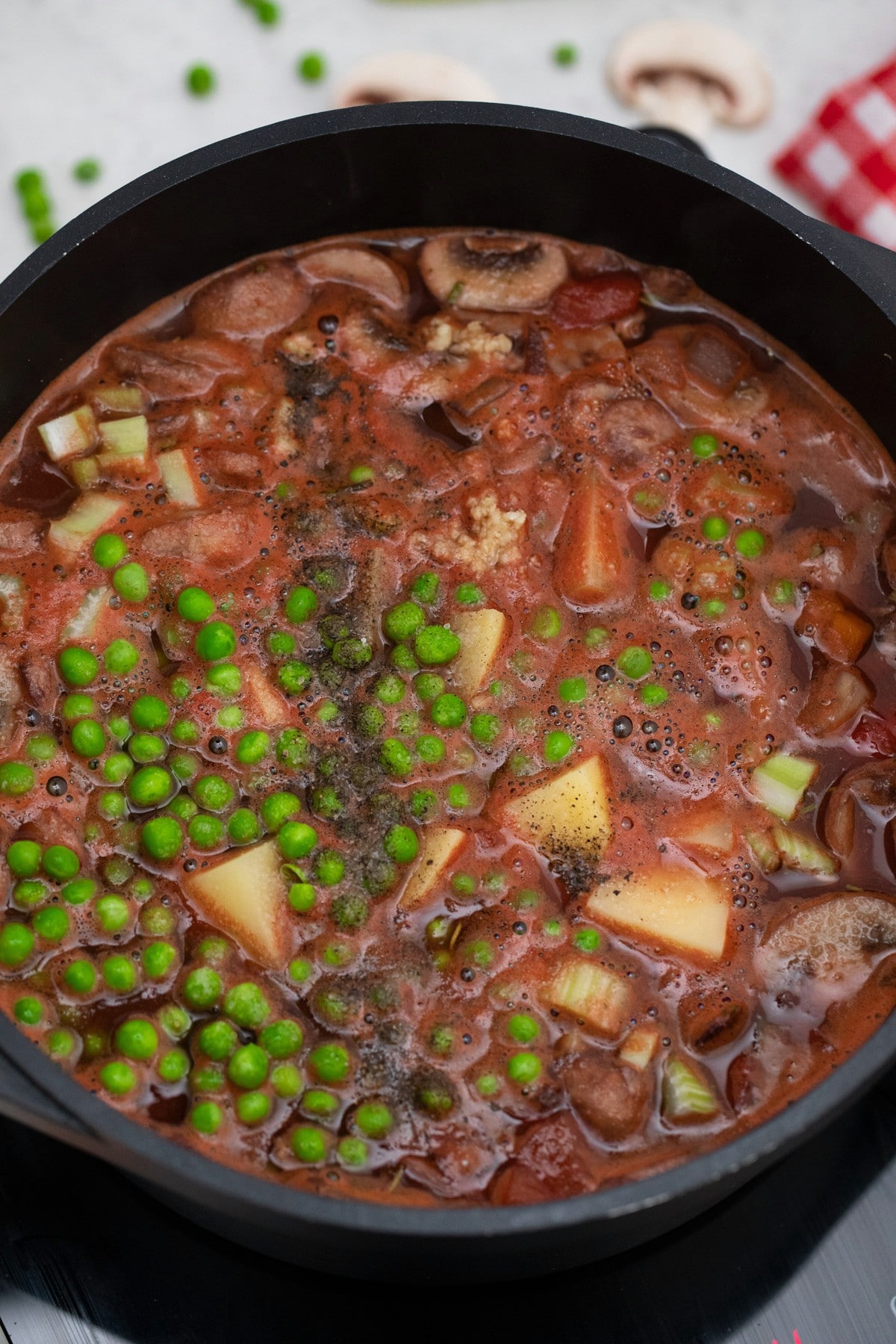 Vegetable soup in dutch oven with peas on top
