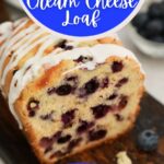 Loaf of blueberry bread on cutting board with blue banner that says blueberry cream cheese bread on image