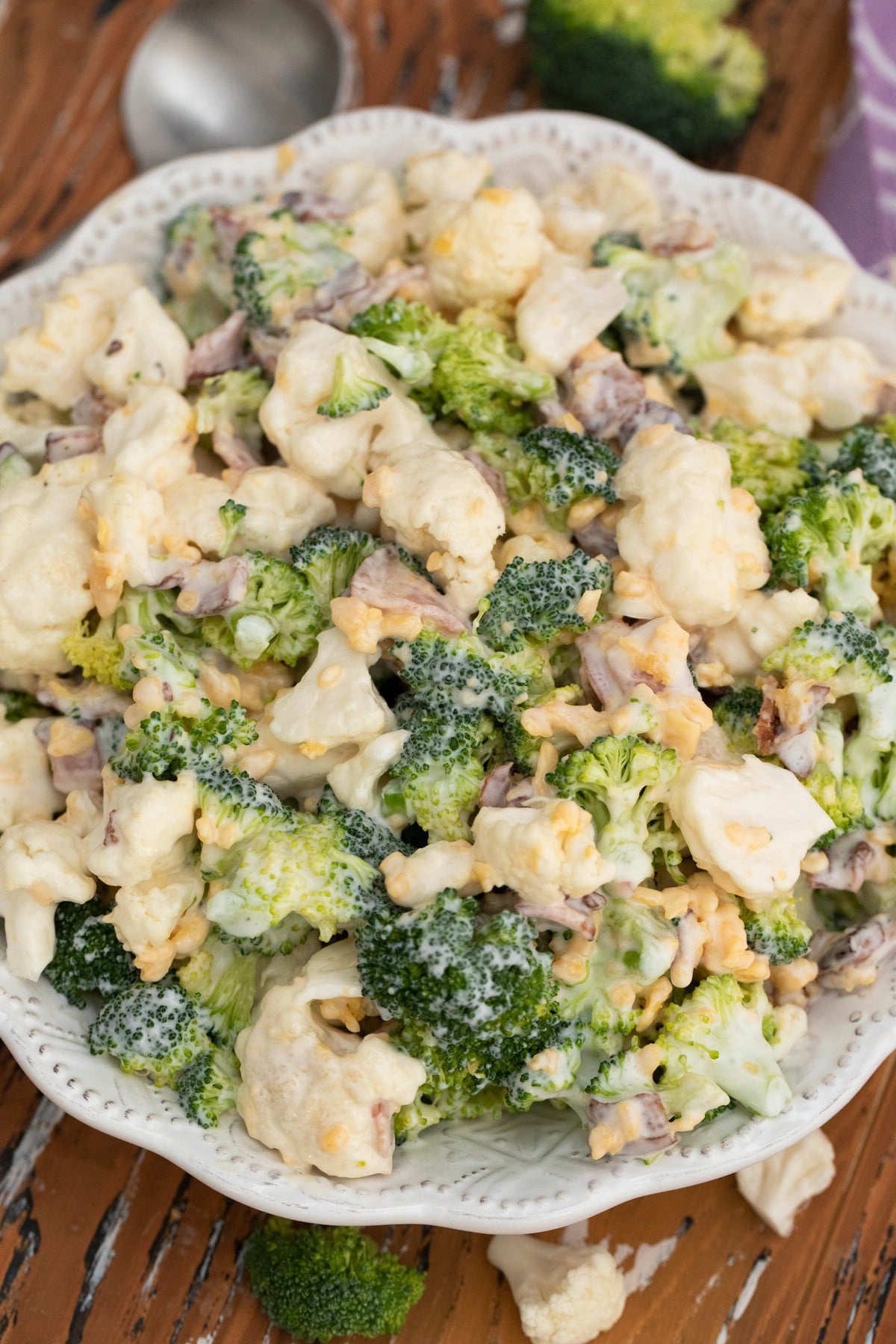 White bowl on table with broccoli and cauliflower salad