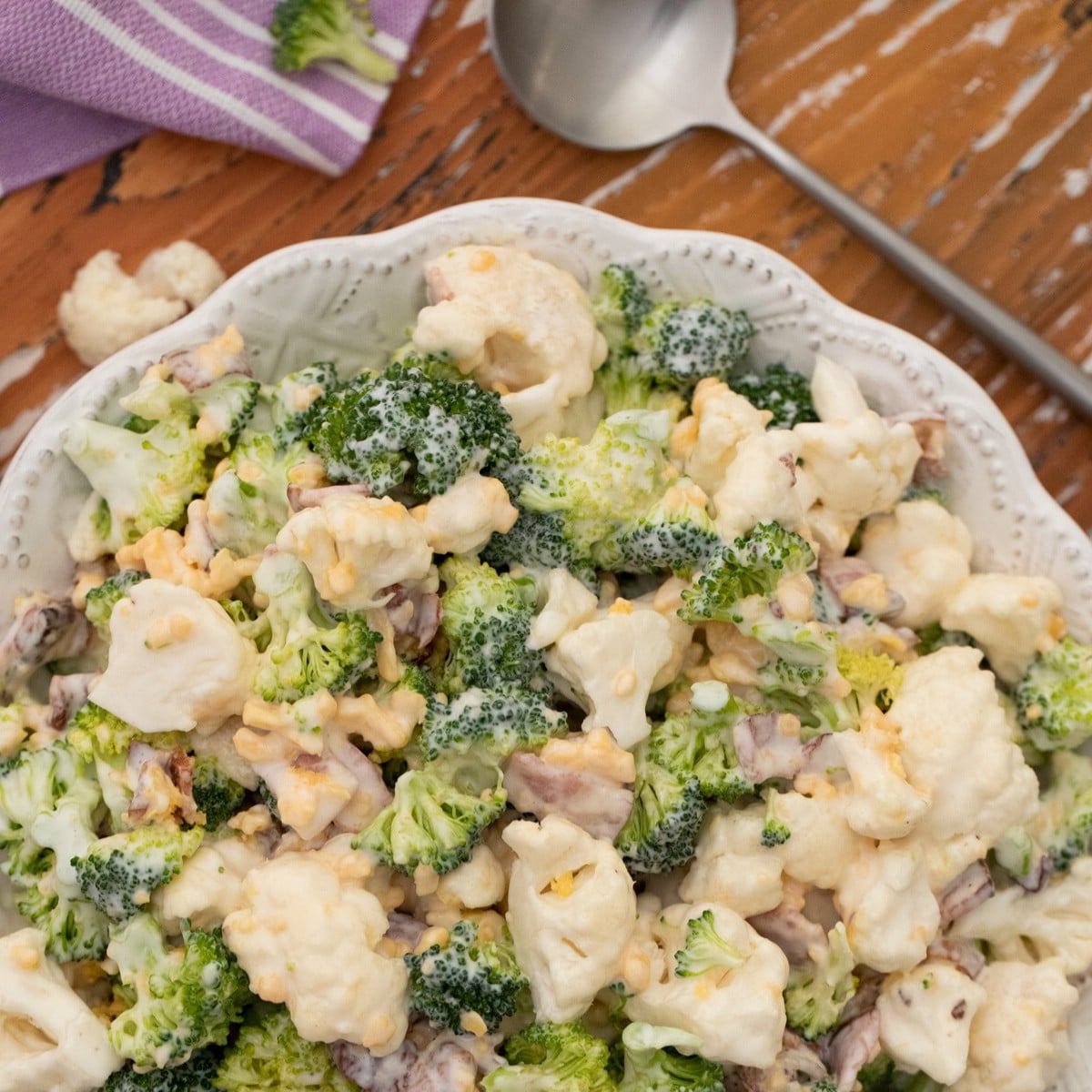 Broccoli salad in a white bowl on wood table