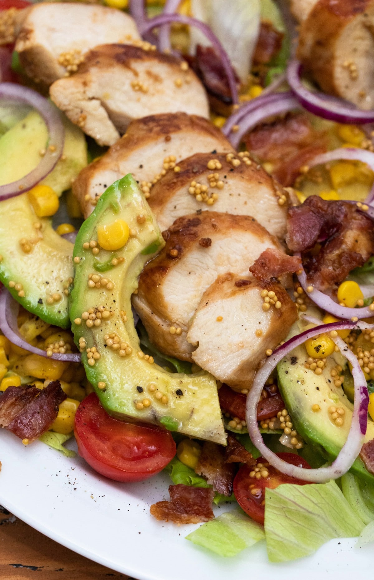 Close up of avocado and chicken on salad with red onions