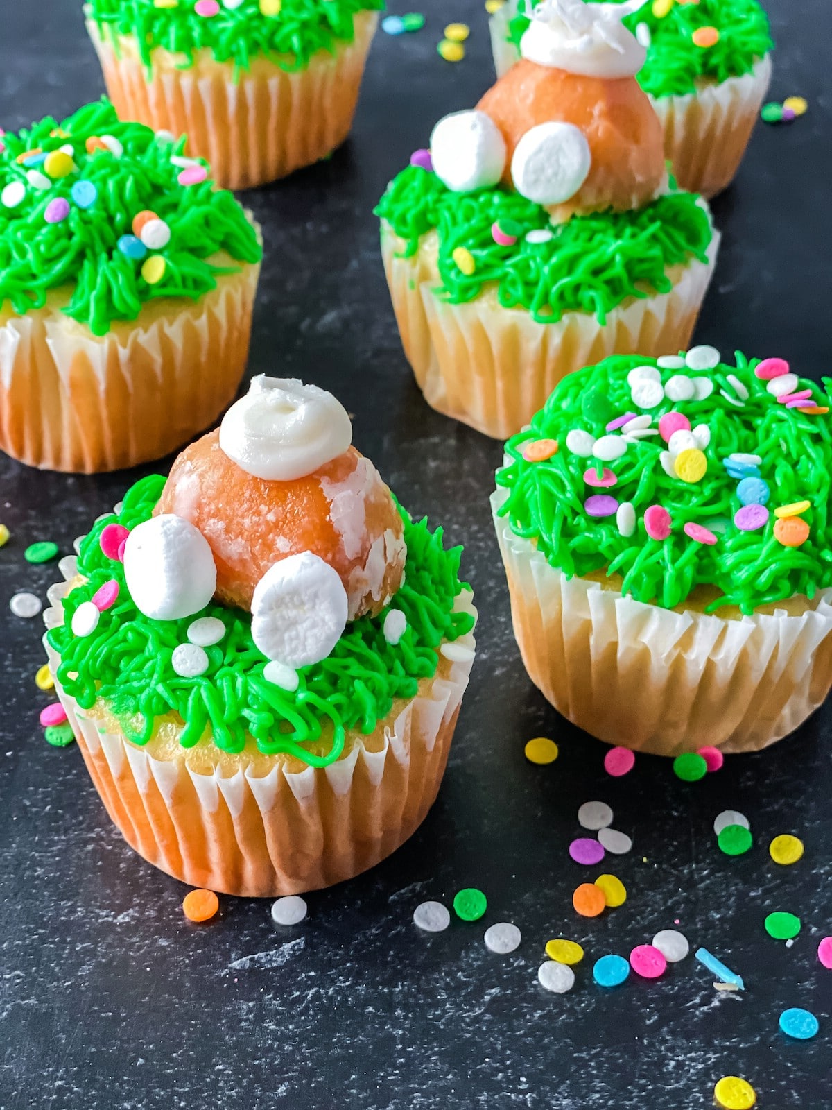 Vanilla cupcake with green icing and donut hole bunny butt