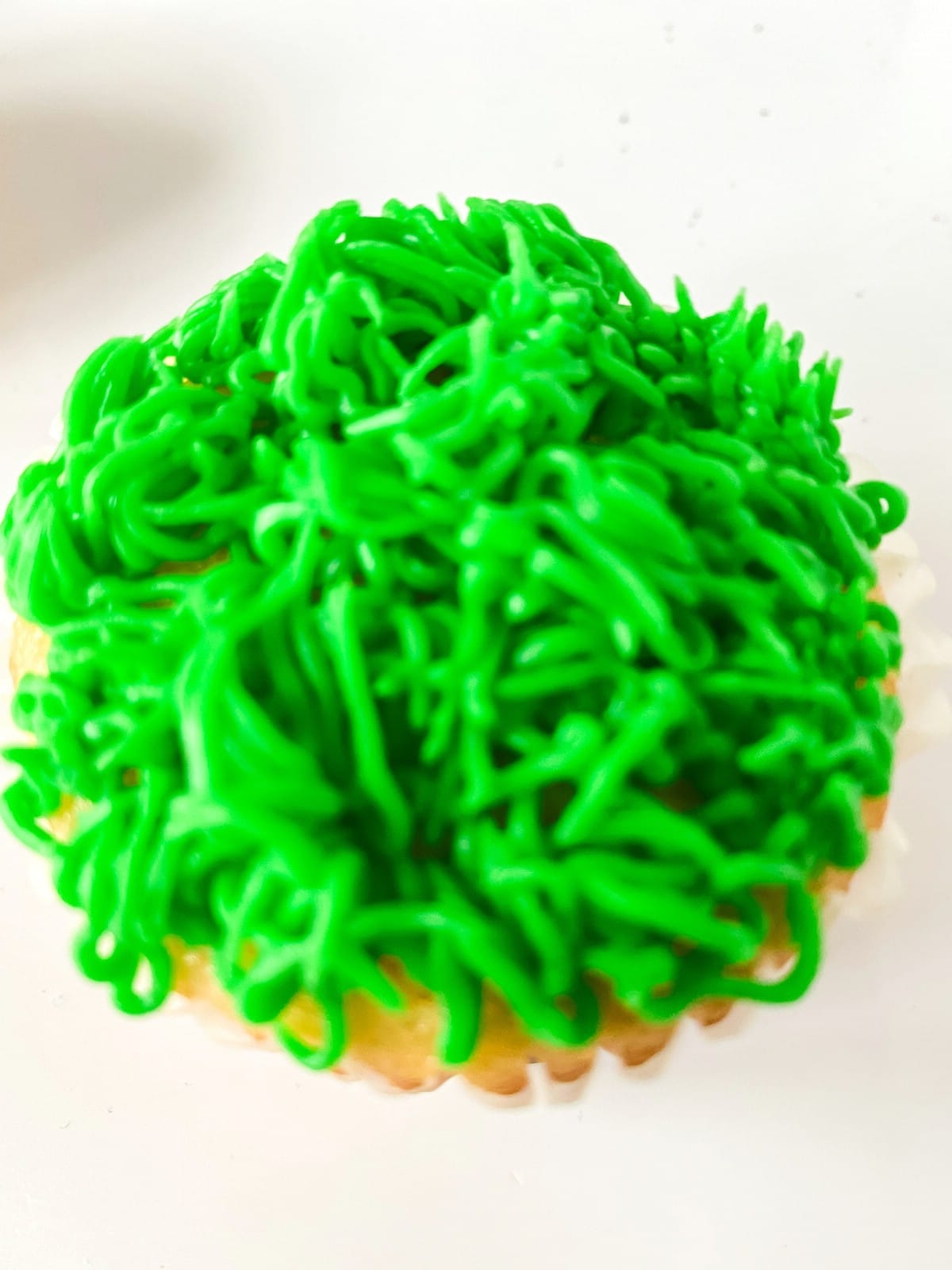 A cupcake topped with green icing like grass
