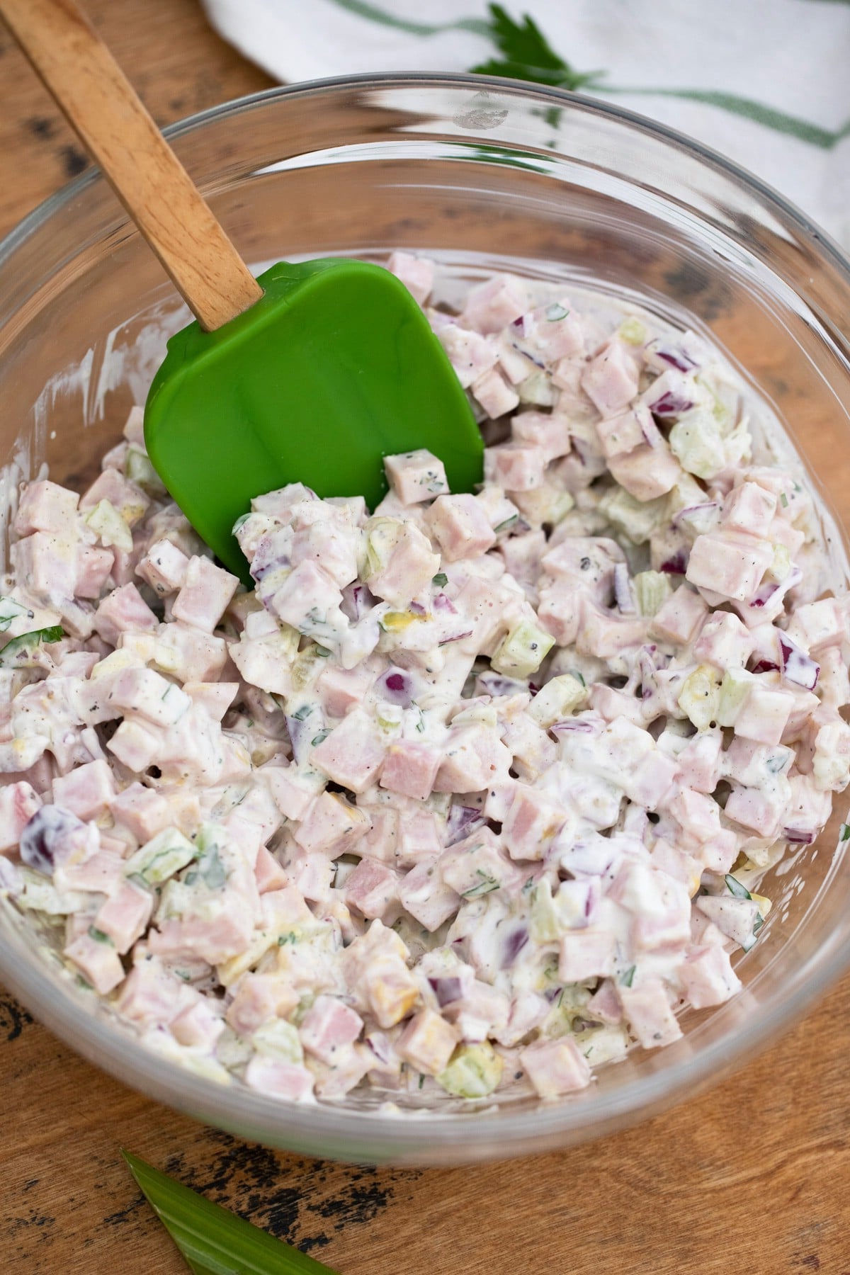 Green spatula in bowl of ham salad