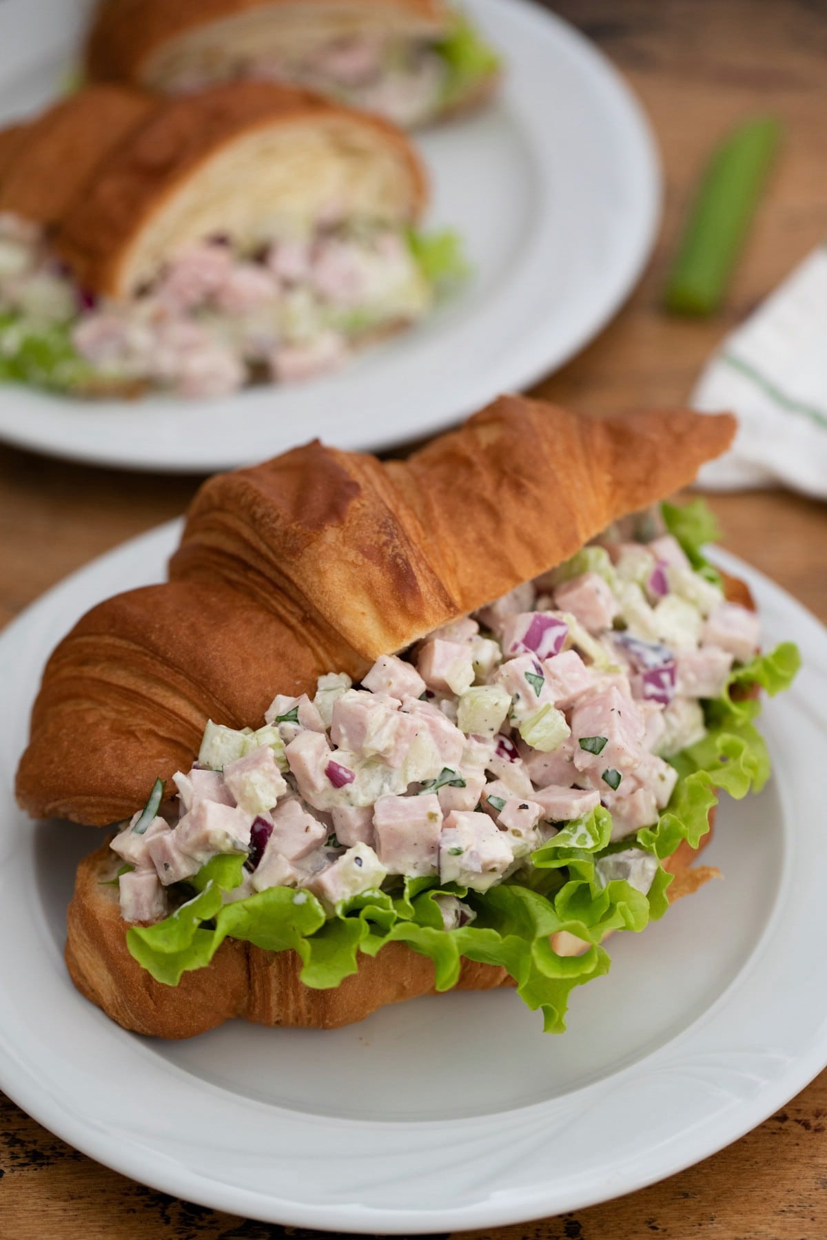 Crossiant with ham salad and lettuce on white plate