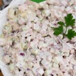 White bowl filled with ham salad topped with parsley