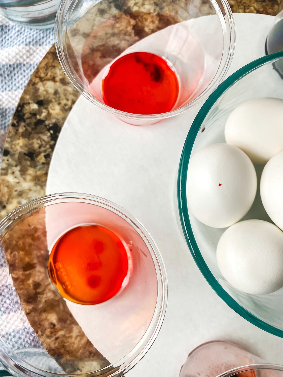 Cups of dyed water on tray with boiled eggs