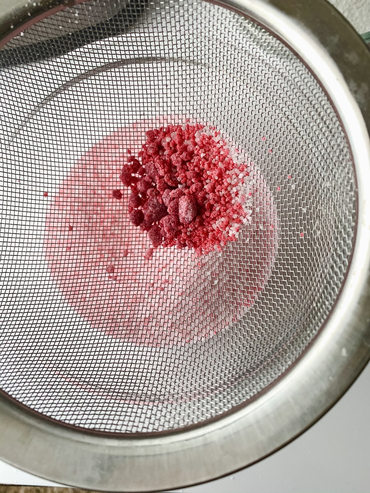 Sugar sifting through fine mesh strainer to remove clumps
