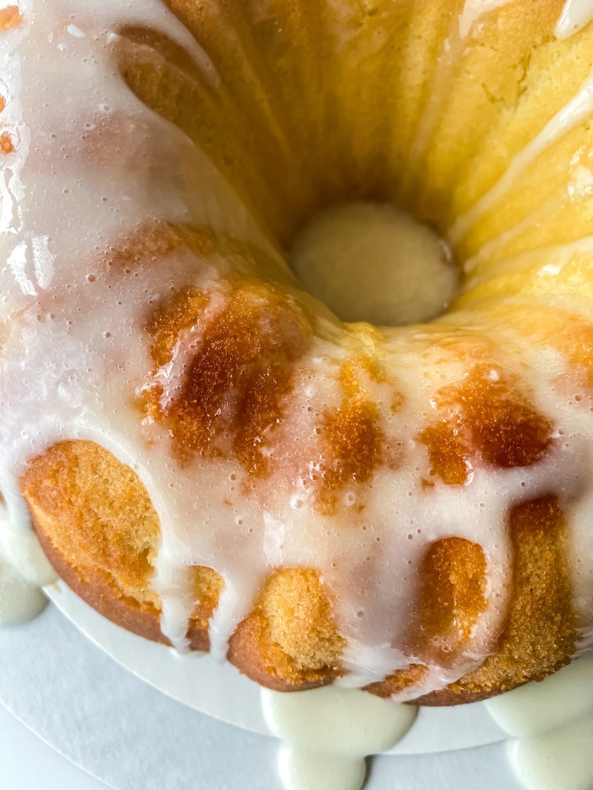 Bundt cake on white cake stand covered with glaze