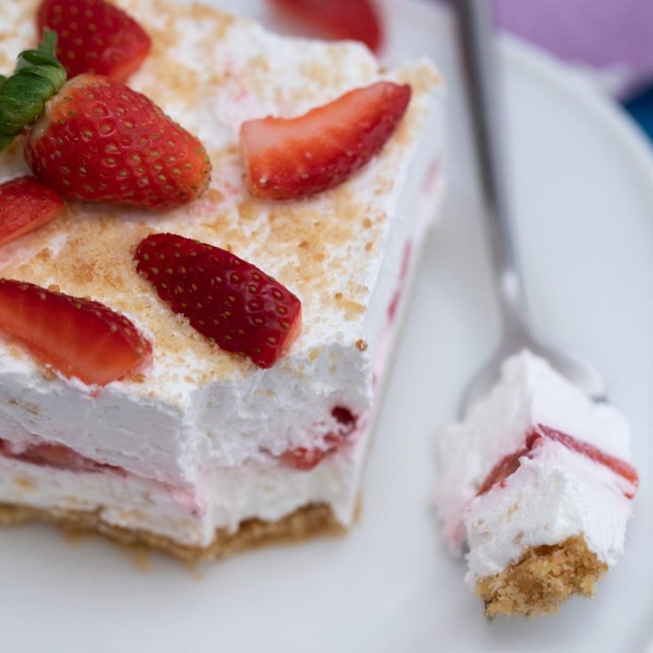 Slice of strawberry dessert on white plate with fork