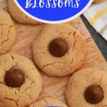 Cookies on cutting board with blue banner over top saying peanut butter blossoms