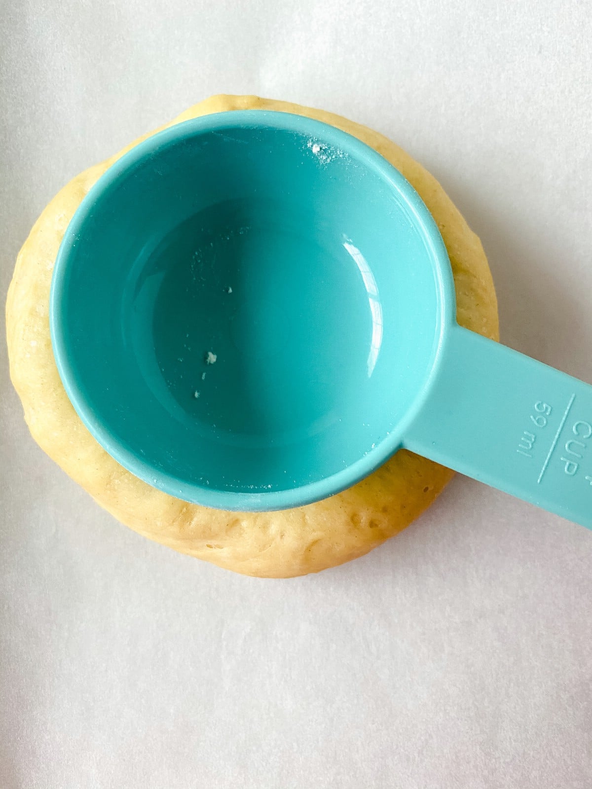 Ball of dough with teal measuring cup on top