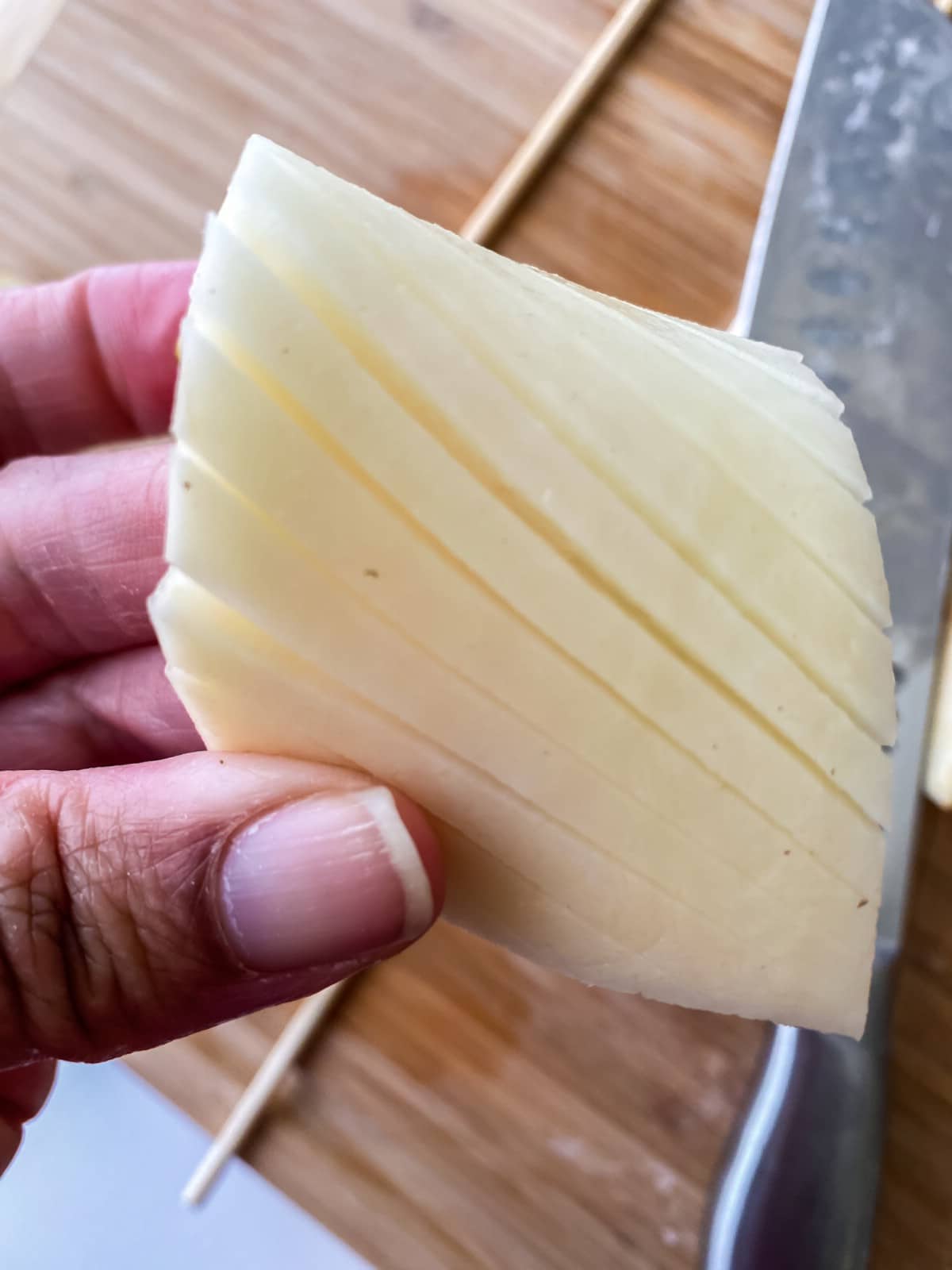Hand holding potato slices above cutting board