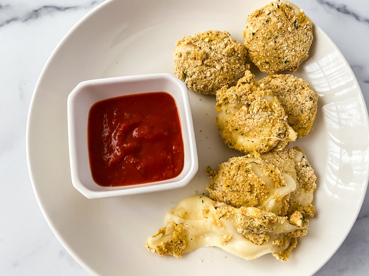 Breadcrumb coated cheese rounds on saucer with sauce